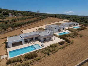 A modern villa with a swimming pool, multiple bedrooms, and a view of the surrounding countryside. - Faragas Hill (Paros Island)