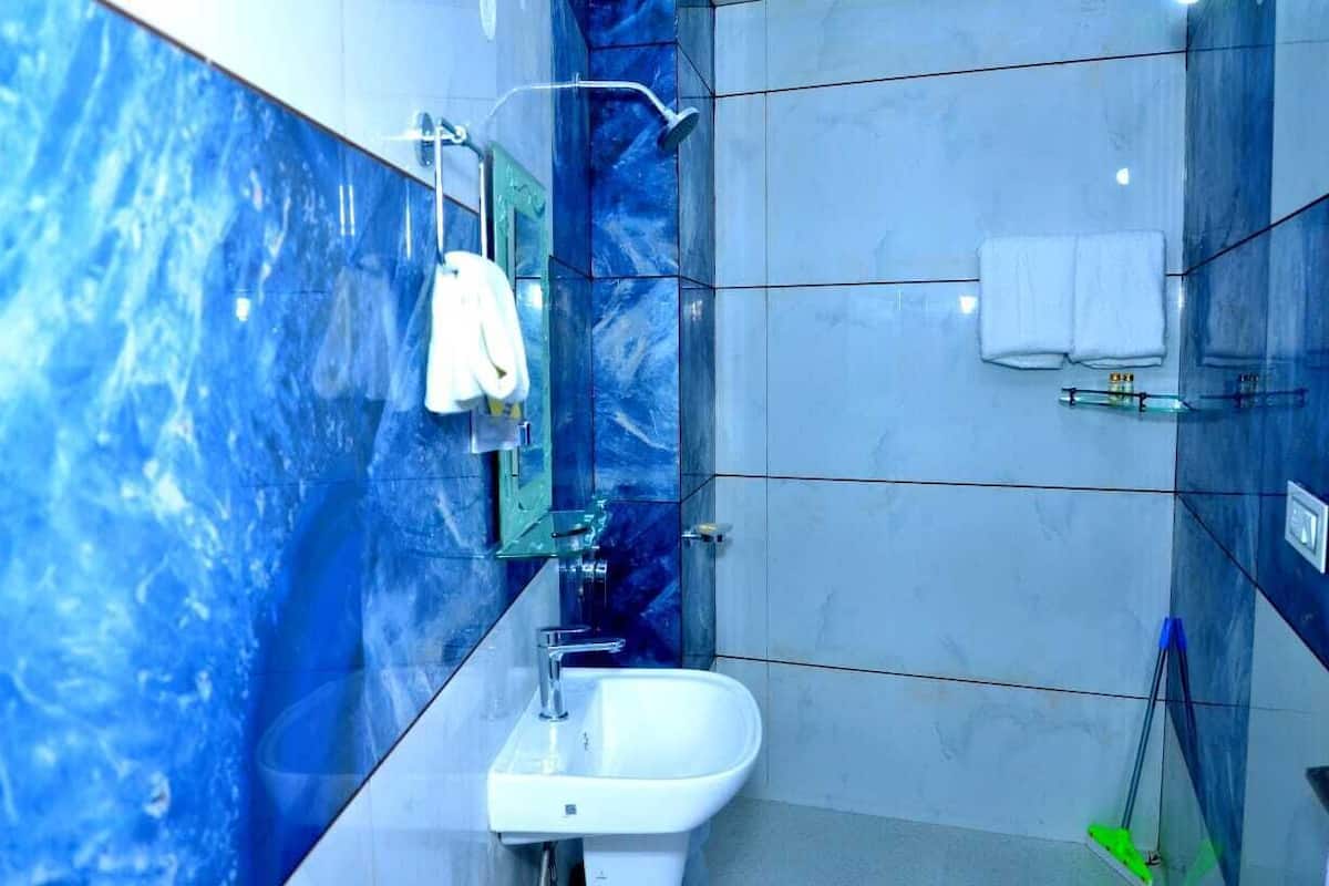 A modern bathroom with a white sink, a glass shower enclosure, and blue marble walls.