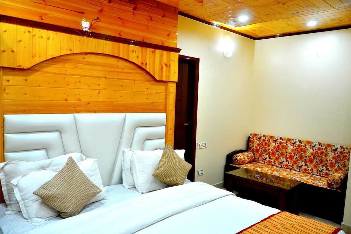 A bedroom with a bed, two pillows, a sofa, and a wooden ceiling.