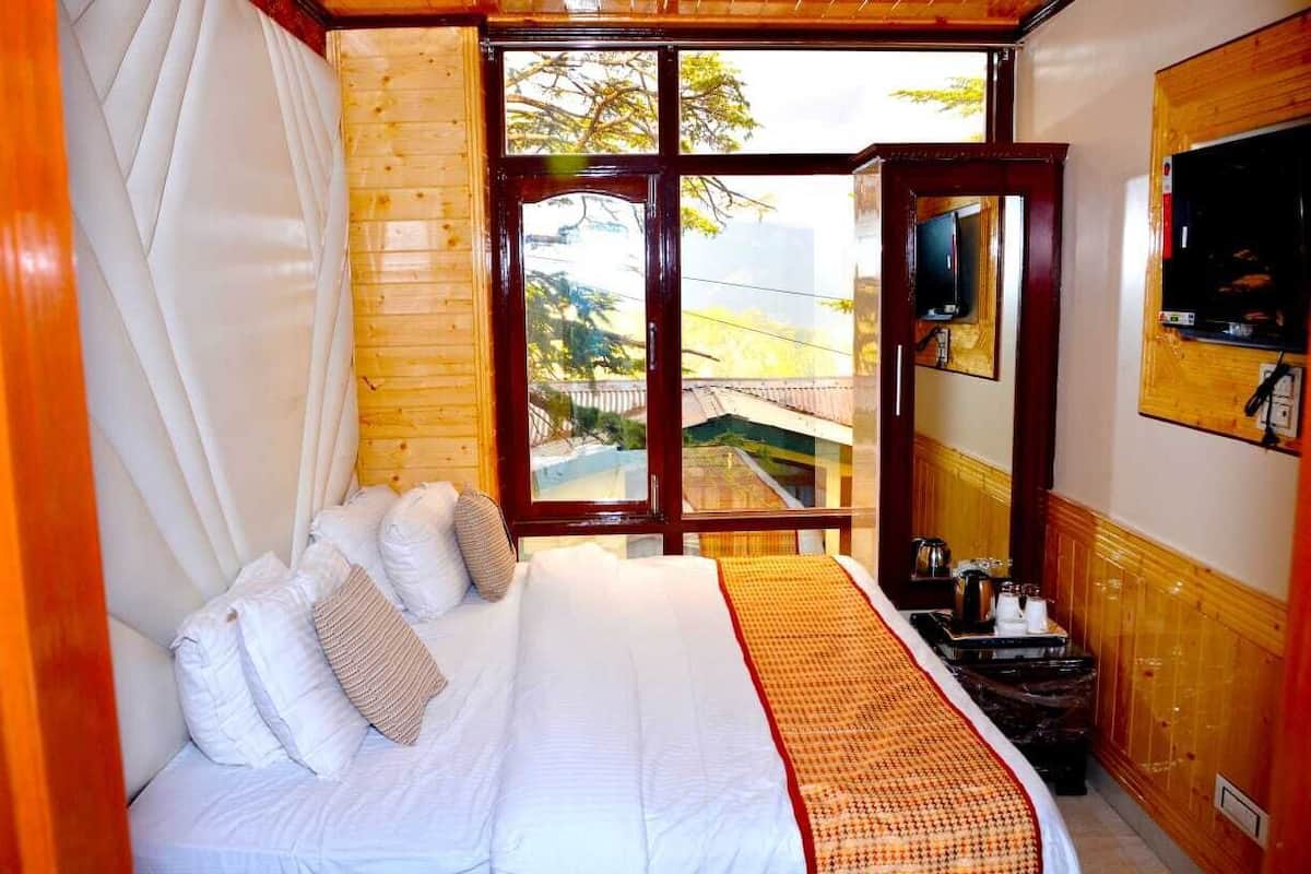 A hotel room with a large bed, a wooden headboard, a television, and a window with a view of a traditional building.