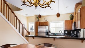 A modern kitchen with wooden cabinets, a stainless steel refrigerator, and a granite countertop. - Chalet 98 at the Official Collins Lake Resort (Government Camp)