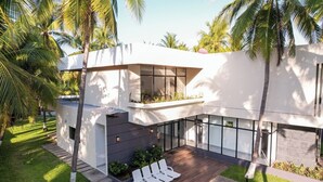 Een modern huis met een zwembad, buitenzitplaatsen en weelderige beplanting.