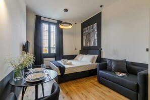 A modern bedroom with a bed, a sofa, a dining table with plates and glasses, and a window with curtains. - Chic Studio in Historical Bovisa, Milan (Milan)