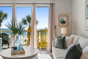 Un soggiorno con divano, tavolino da caffè e vista sul mare da un balcone.