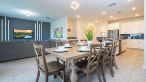 Una cocina moderna con armarios blancos, una mesa de comedor para seis personas y una isla grande.