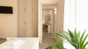 A hotel room with a bed, a TV mounted on the wall, and a wooden wardrobe. - Stone villa with private heated pool close to Marathi beach (Kounoupidiana)