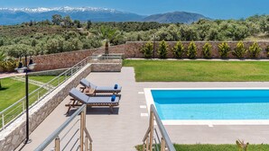 A pool area with lounge chairs and a stone wall. - Stone villa with private heated pool close to Marathi beach (Kounoupidiana)
