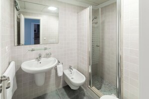 A bathroom with a sink, bidet, and glass-enclosed shower. - Camelot - Apartment (Oliva)