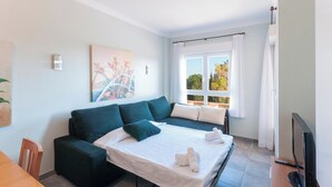 A modern room with a sofa bed, a flat-screen TV, and a painting on the wall. - Camelot - Apartment (Oliva)