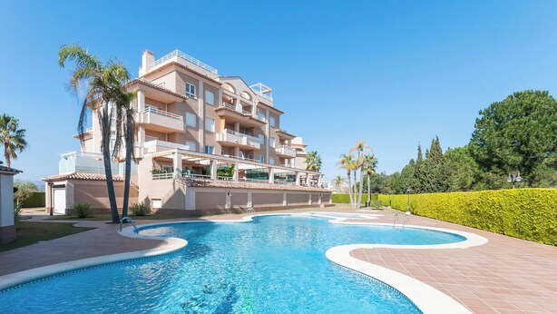 A swimming pool with a modern building in the background. - Camelot - Apartment (Oliva)