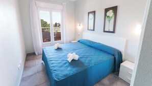 A bedroom with a large bed, a nightstand, and a window with curtains. - Camelot - Apartment (Oliva)