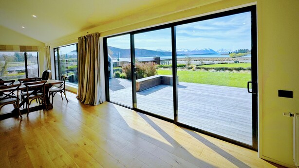 A spacious room with large sliding glass doors leading to an outdoor deck. - Cedar View (Lake Tekapo)
