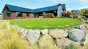 A modern house with a sloped roof, large windows, and a stone chimney. - Cedar View (Lake Tekapo)