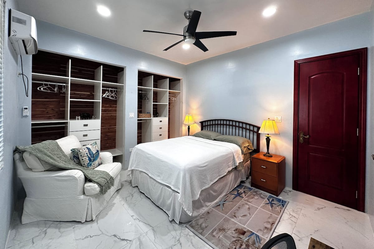 A bedroom with a bed, bedside tables, a wardrobe, and a ceiling fan.
