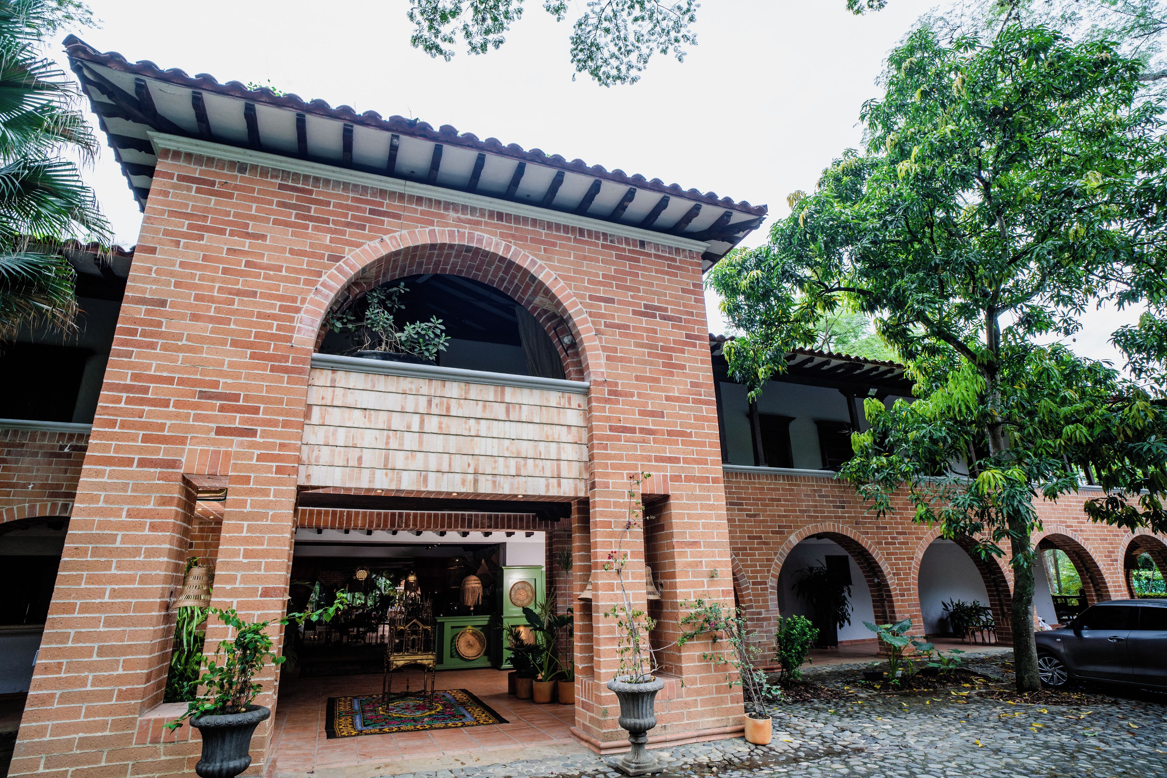 A brick building with a tiled roof, arched doorways, and potted plants.