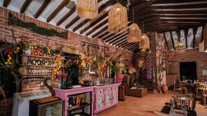 A rustic interior with exposed brick walls, wooden beams, and hanging wicker lamps. - Casa Cielo Al Alma (Santa Fe de Antioquia)