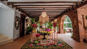 A hallway with a patterned rug, a central table with flowers, and a hanging light fixture. - Casa Cielo Al Alma (Santa Fe de Antioquia)