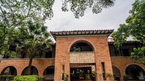 A courtyard with a brick building featuring arched doorways and a tiled roof. - Casa Cielo Al Alma (Santa Fe de Antioquia)