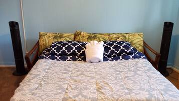 A bed with a patterned bedspread, two pillows with a floral design, and two wall-mounted paintings of sea creatures.