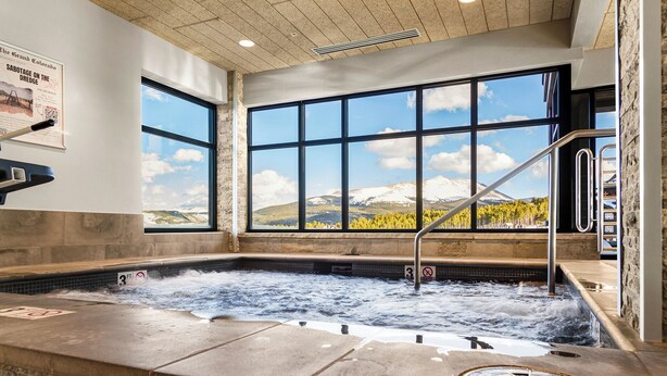 A hot tub with a view of mountains and trees through large windows. - Grand Colorado on Peak 8 2 BD Colorado ski-in/out (Breckenridge)