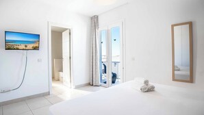 A hotel room with a bed, a TV, a shower, and a balcony with a view.