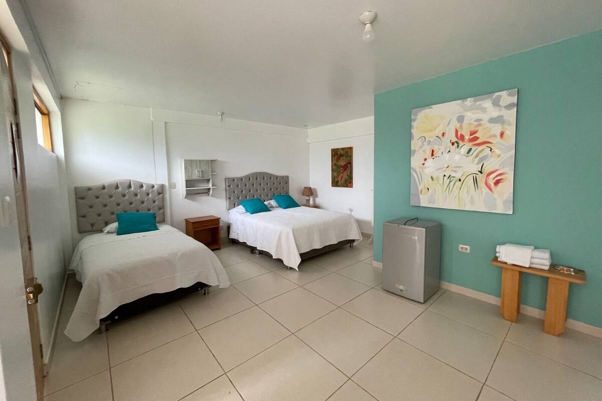 Une chambre d’hôtel avec deux lits, un petit bureau, un réfrigérateur et un tableau au mur.