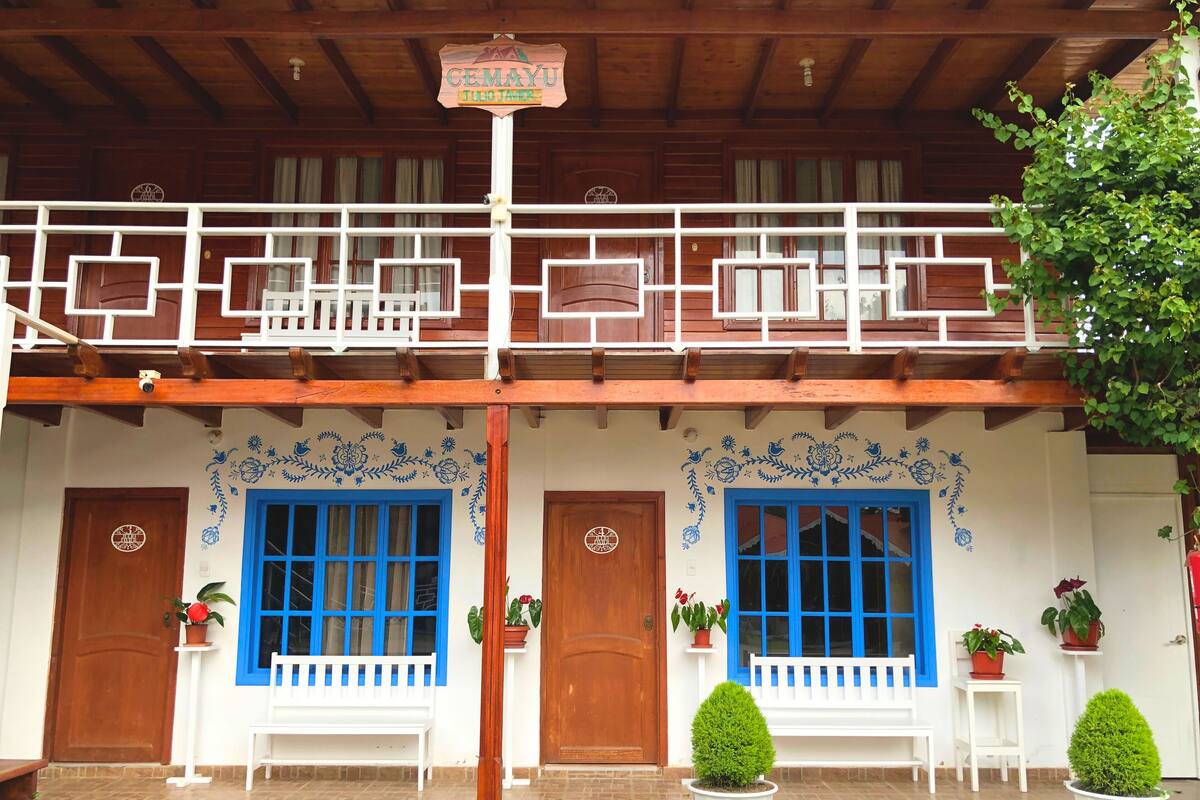 Un bâtiment traditionnel en bois, doté d’un balcon, de fenêtres à cadre bleu et de plantes en pot.