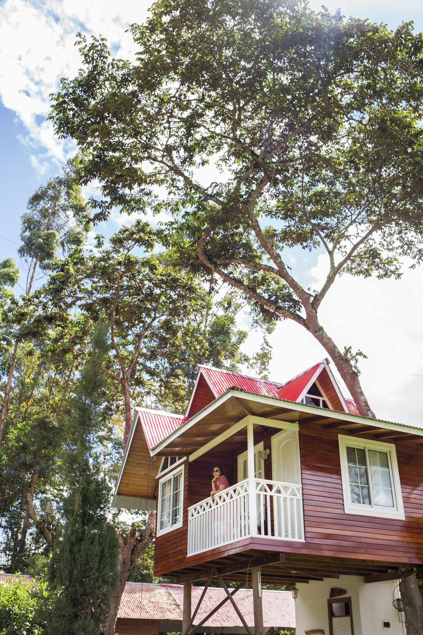 A wooden house with a balcony, surrounded by trees.