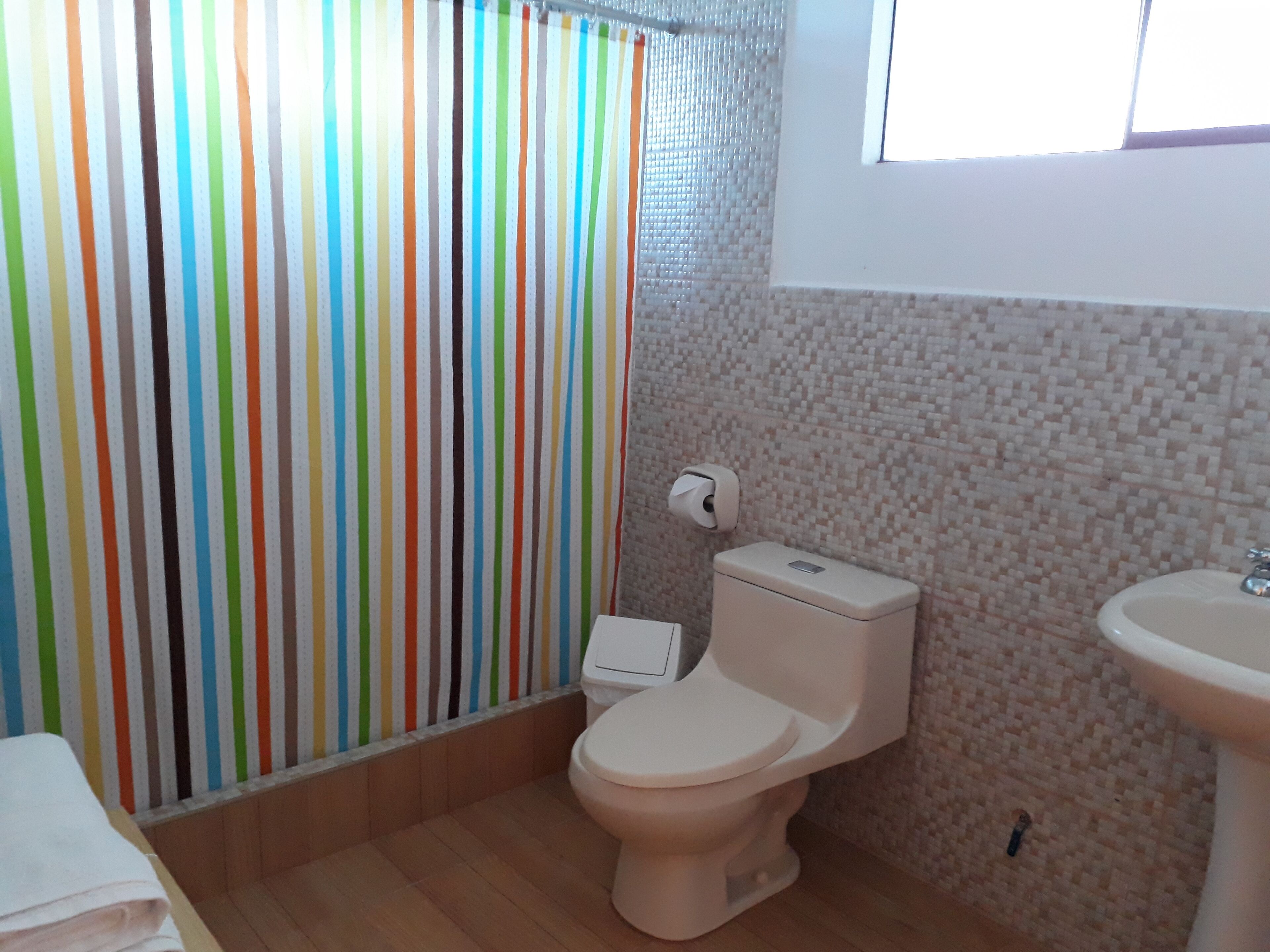 A bathroom with a toilet, sink, and a shower curtain with vertical stripes.