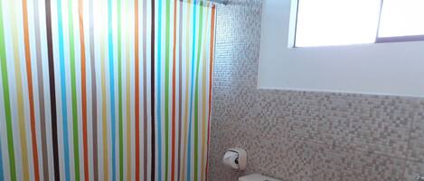 A bathroom with a toilet, sink, and a shower curtain with vertical stripes.