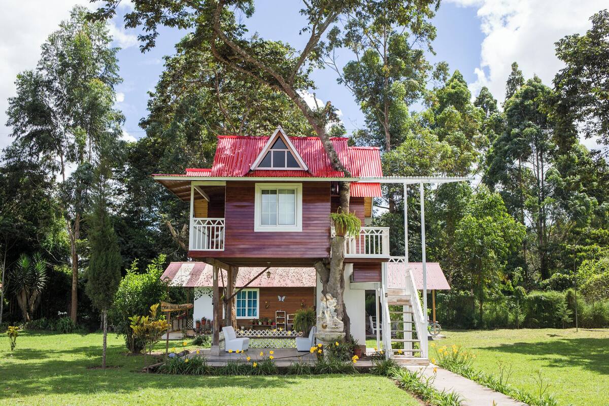 Une maison à deux étages avec un toit rouge et un balcon.