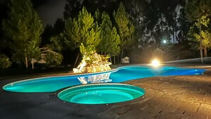 Una piscina con fuente, rodeada de árboles y un deck pavimentado.