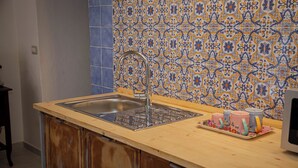 A kitchen with a wooden countertop, a stainless steel sink, and a tiled backsplash. - Cozy studio apartment within walking distance of the Archaeological Excavations of Pompeii (Scafati)