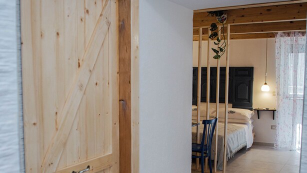 A wooden door leading into a room with a bed, a chair, and a hanging plant. - Cozy studio apartment within walking distance of the Archaeological Excavations of Pompeii (Scafati)