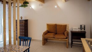 A cozy room with a wooden sofa, a dining table, and a coffee machine. - Cozy studio apartment within walking distance of the Archaeological Excavations of Pompeii (Scafati)