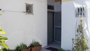 A courtyard with potted plants, a metal gate, and a small window. - Cozy studio apartment within walking distance of the Archaeological Excavations of Pompeii (Scafati)