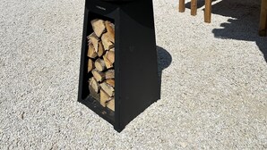A patio area with a wood-burning stove, a wooden table, and a potted plant. - Gîte de Condeiss (Condeissiat)