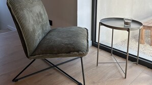 A modern room with a single green upholstered chair and a small round table with a glass. - Gîte de Condeiss (Condeissiat)