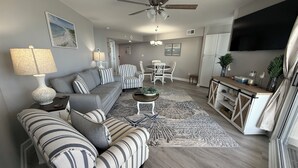 Un salon moderne avec un canapé gris, des fauteuils à rayures, une table basse et un tapis à motifs.