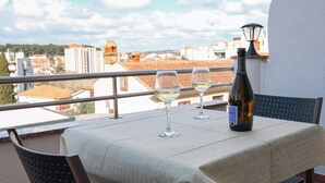 Ein Balkon mit einem Tisch für zwei Personen, zwei Weingläsern und einer Weinflasche.