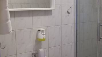 A bathroom with a white sink, a mirror, and a glass shower enclosure.