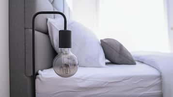A bed with a headboard, a bedside lamp, and pillows.