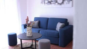 Ein modernes Wohnzimmer mit einem blauen Sofa, einem runden Couchtisch und zwei Hocker.
