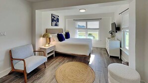 Una camera da letto moderna con un letto, un comodino, una lampada e vista sull'esterno.