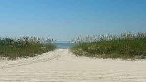 A sandy beach path leading to the ocean, bordered by tall grasses. - Beautiful Sunset and Gulf Views-2 bedroom / 2 bathroom (Biloxi)