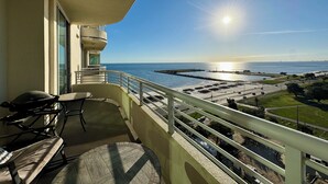 A balcony with a view of the sea, a table, and a chair. - Beautiful Sunset and Gulf Views-2 bedroom / 2 bathroom (Biloxi)