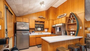 Una cocina con armarios de madera, un refrigerador de acero inoxidable, horno empotrado y una zona de bar con taburetes.