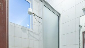 A bathroom with white tiled walls, a shower with a glass door, and a visible window above the shower. - Nairobi Fahari Tripple Suites (Nairobi)