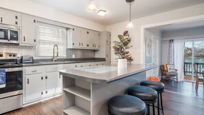 Una cocina moderna con una isla central, electrodomésticos de acero inoxidable y vistas a un balcón.