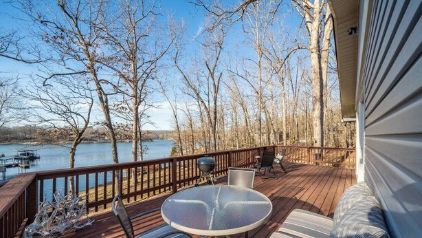 Una terraza con mesa y sillas, con vista a un lago y árboles.